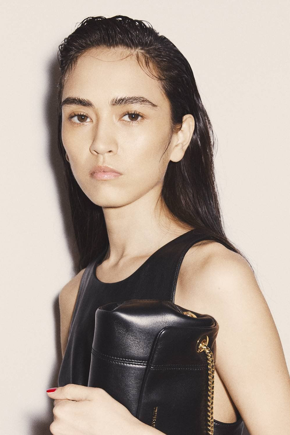 Nora Isaeva con cabello efecto mojado, vestido negro y bolso posando para Generation Models