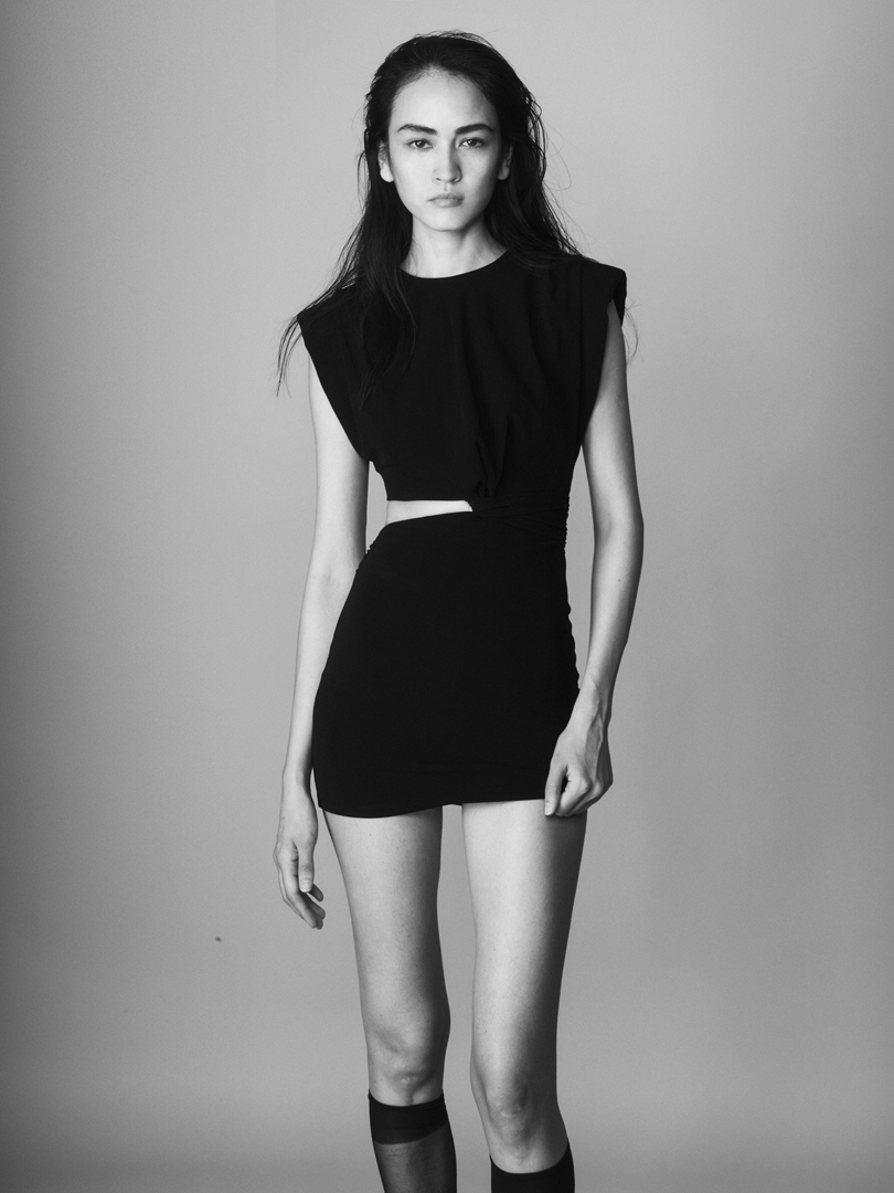 Nora Isaeva con cabello efecto mojado, vestido negro y bolso posando para Generation Models